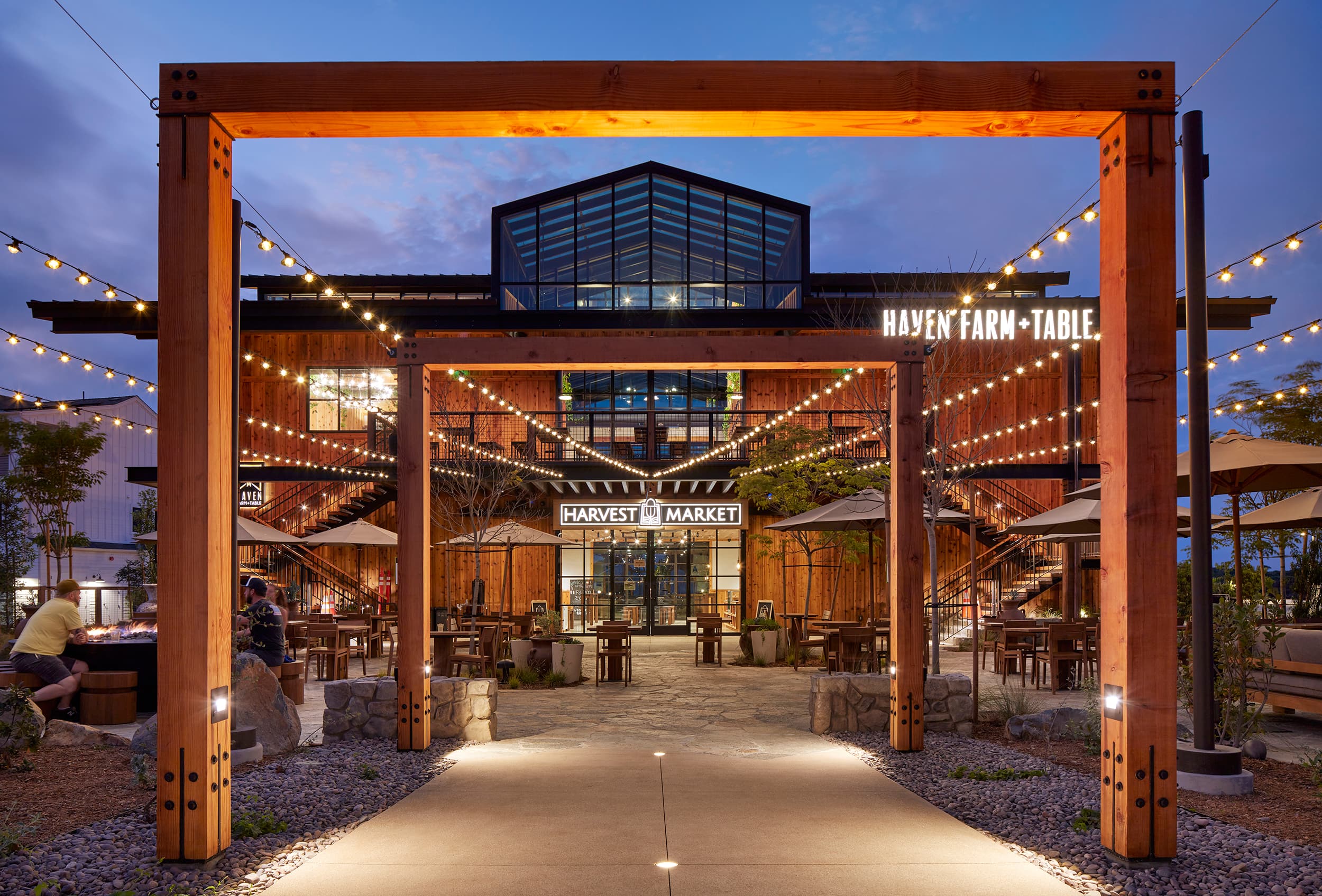 Fox Point Farms in Encinitas at dusk, a timber-framed entry with string lights leading into the market and restaurant