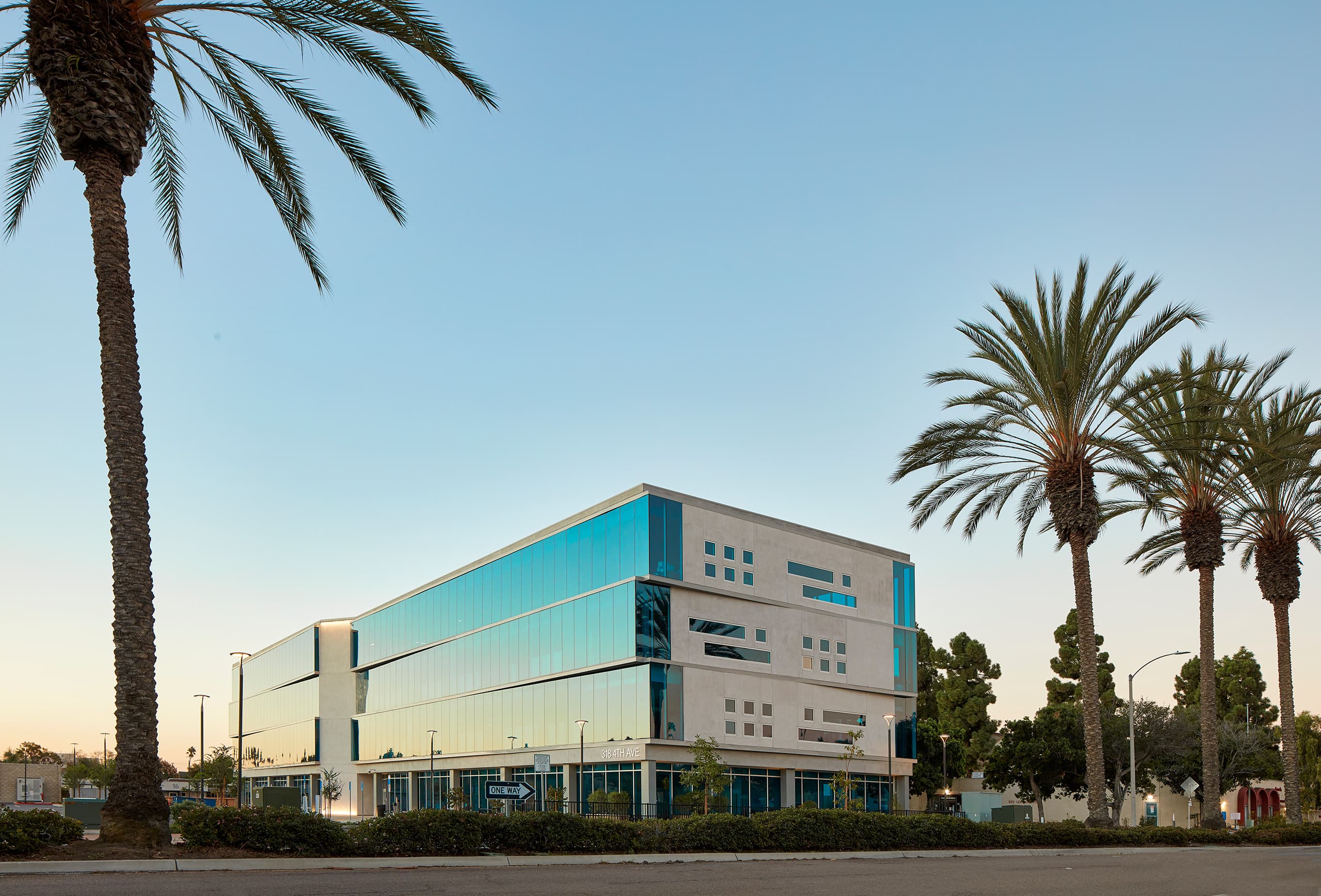 SBCS Administration Building in Chula Vista at dusk, a four-storey glass and concrete office framed by palm trees